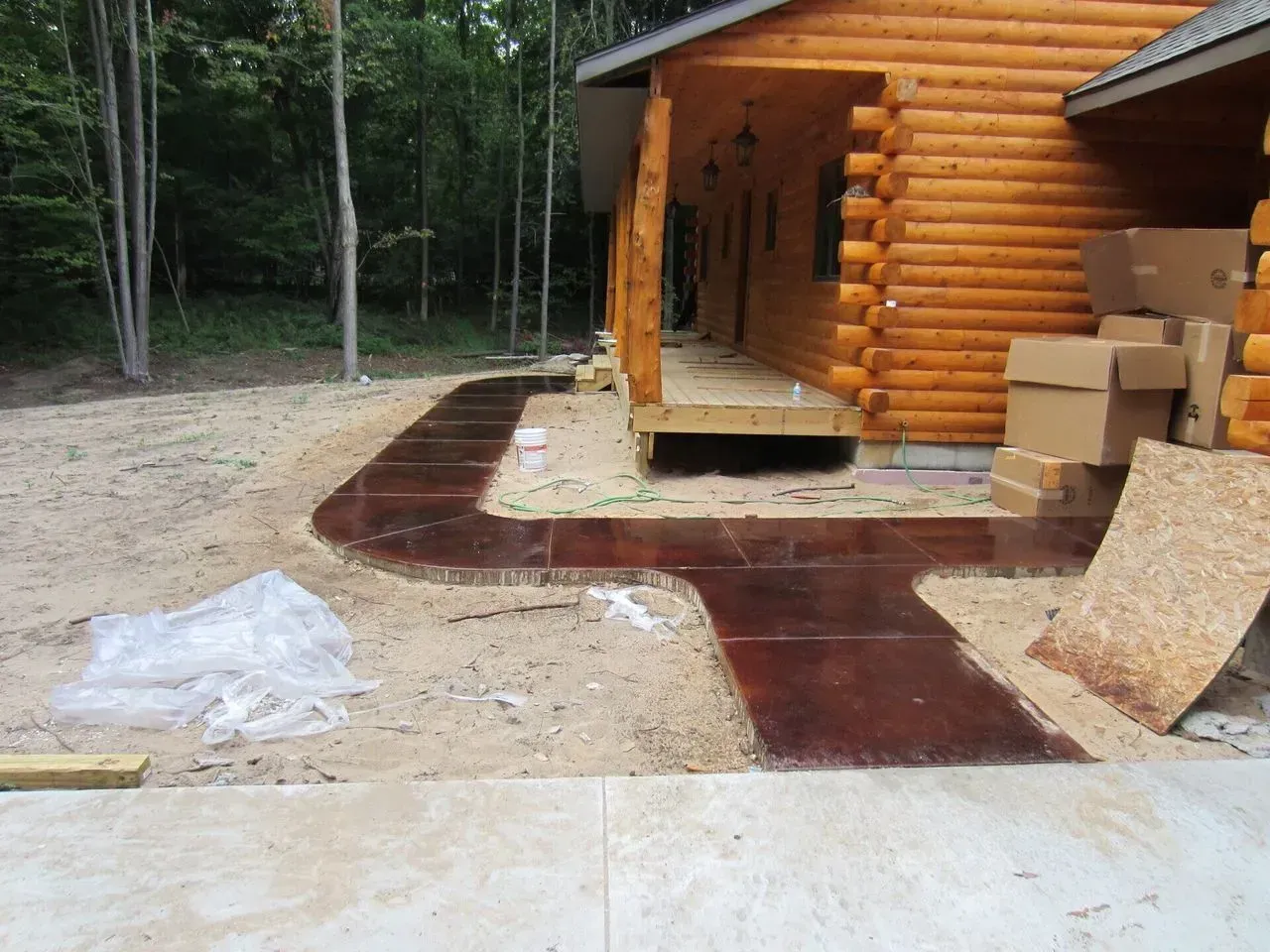A log cabin with a concrete walkway in front of it
