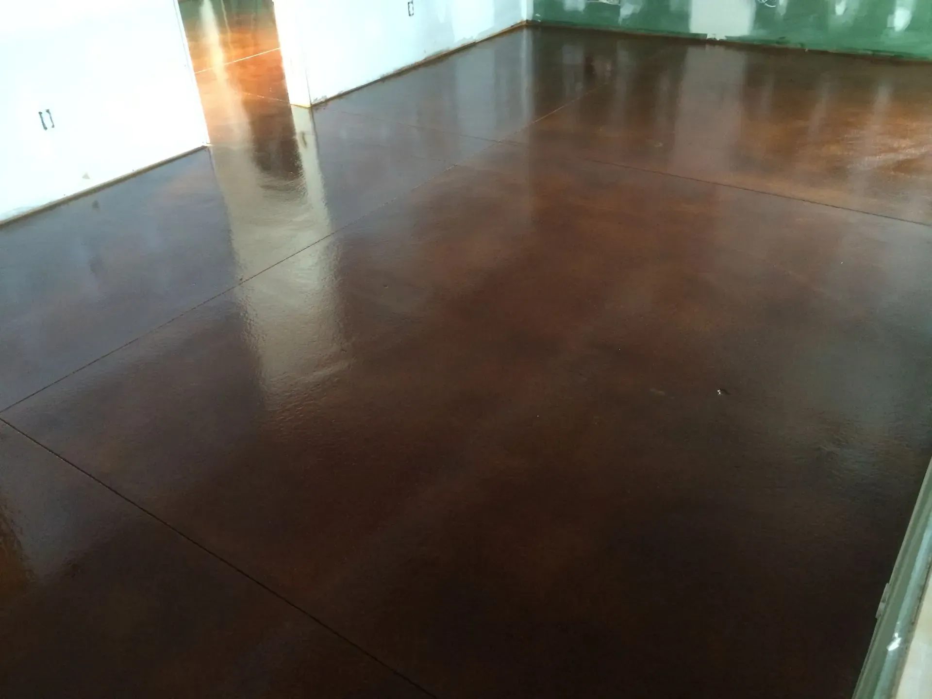A dark brown concrete floor in a room with white walls.