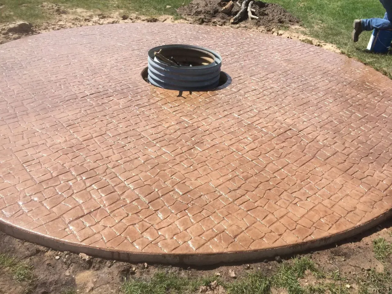 A circular concrete patio with a fire pit in the middle.