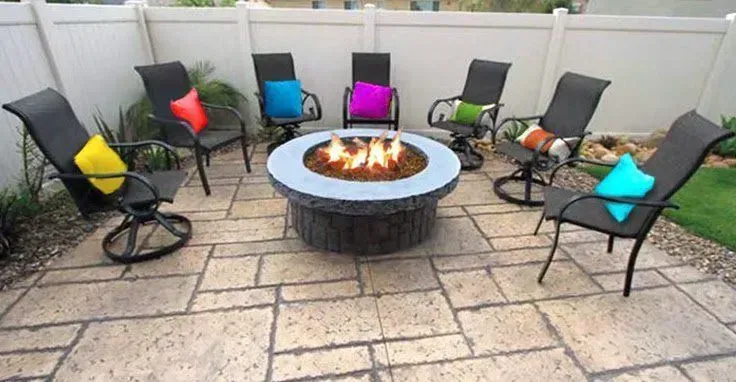 A group of chairs are sitting around a fire pit on a patio.