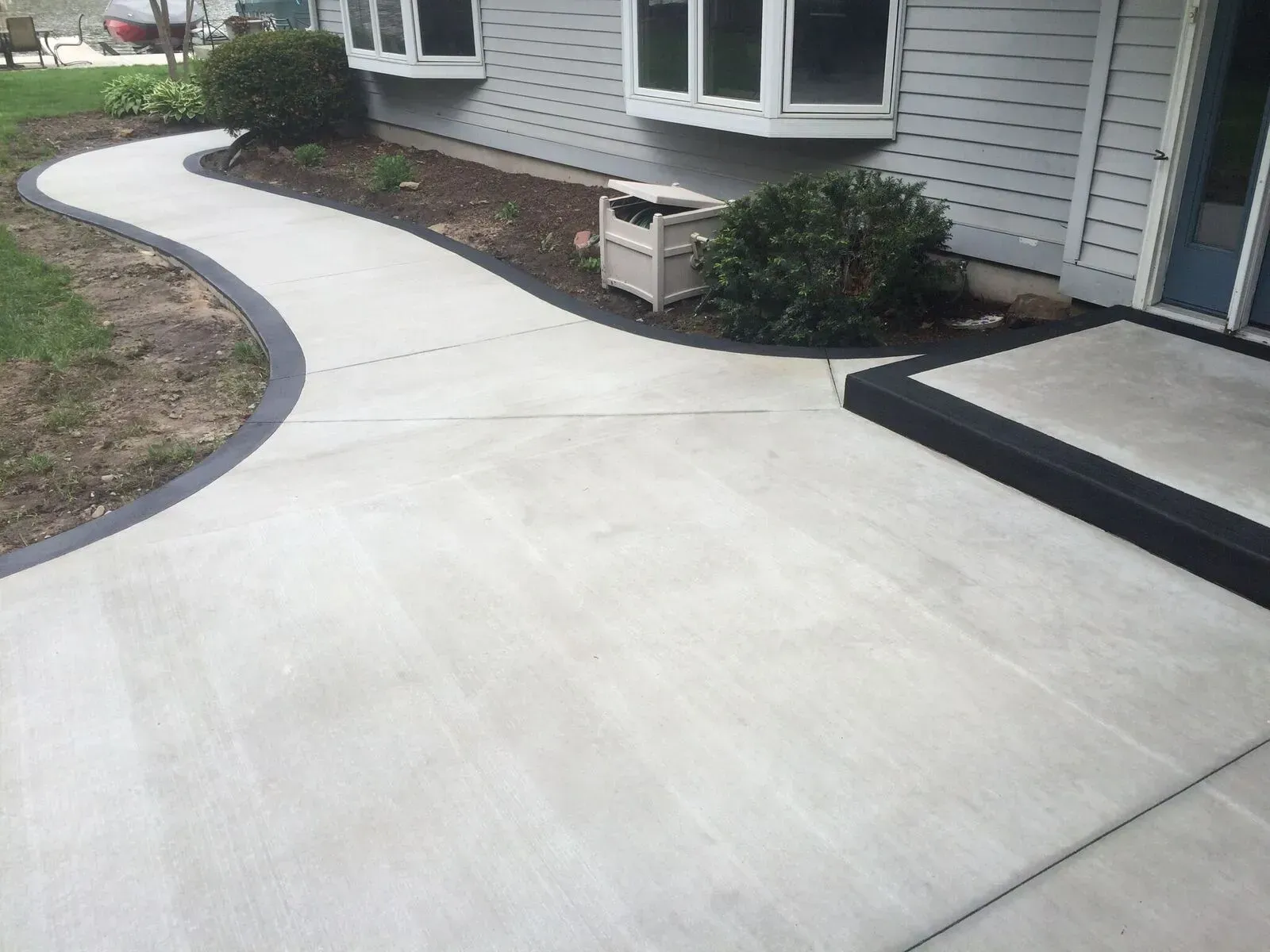 A concrete walkway leading to a house with a black border.