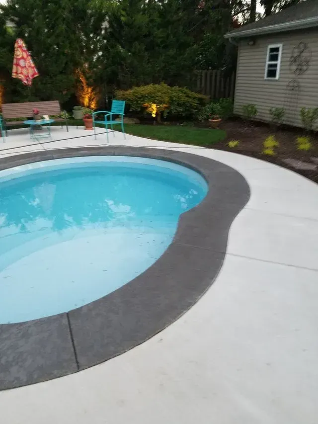 A large swimming pool with a house in the background