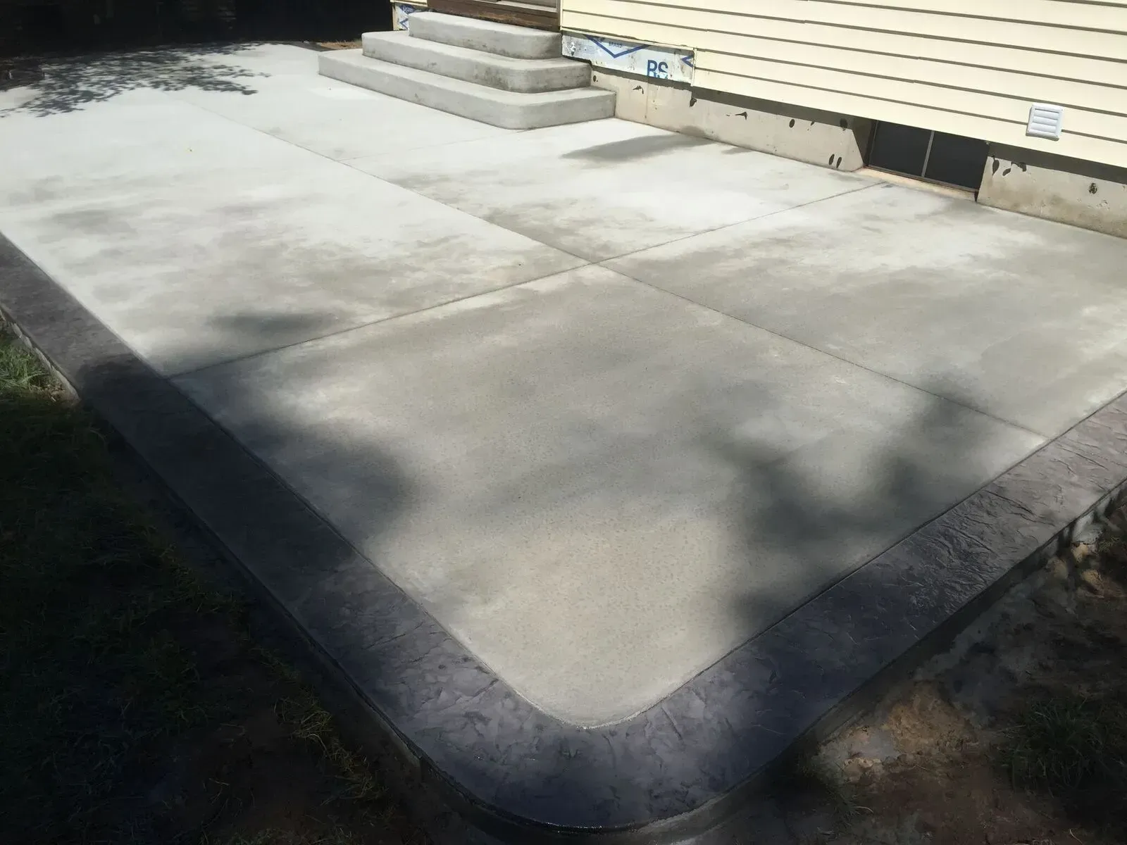 A concrete patio with steps and a house in the background