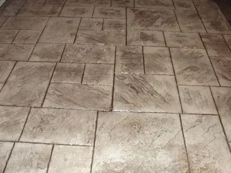 A close up of a concrete floor with square tiles.
