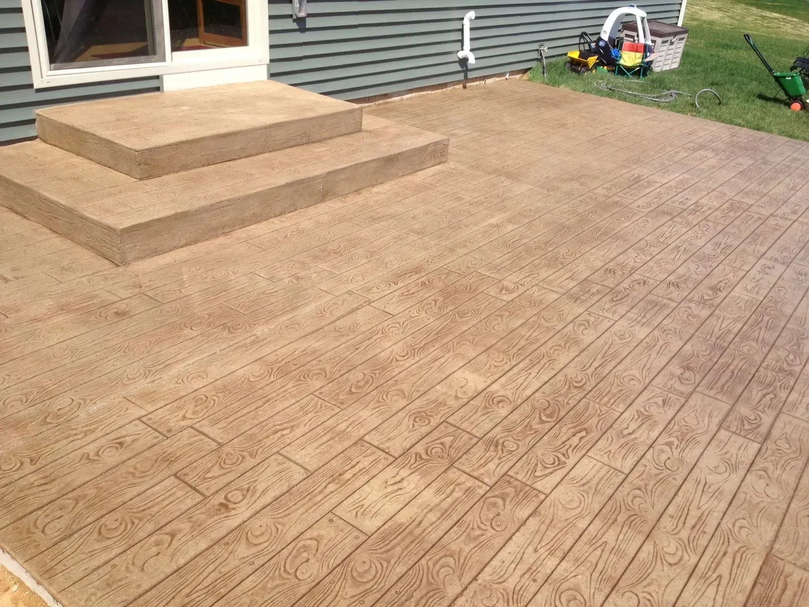 A patio with stairs and a wooden floor in front of a house.