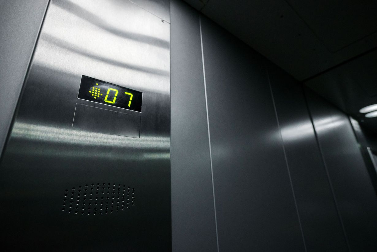 Elevator interior. Digital display shows "07" in green. Silver metal walls.