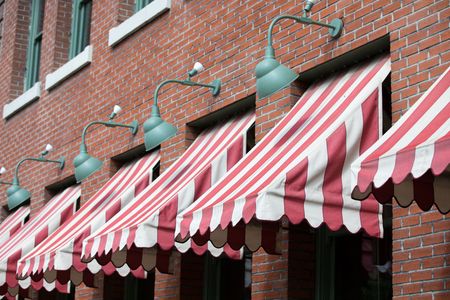 A row of red and white awnings on a brick building.