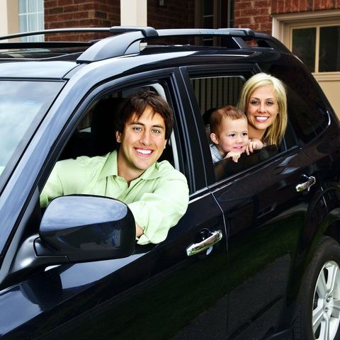 A man and woman are sitting in a car with a baby