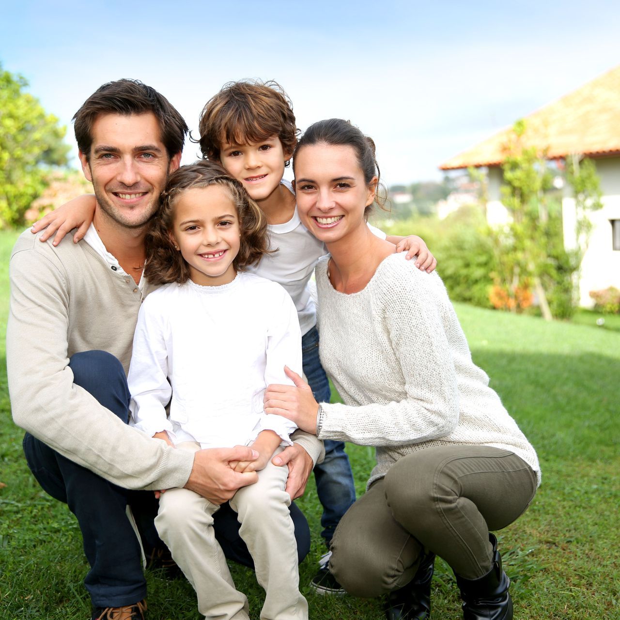 A family posing for a picture in the grass in front of a house