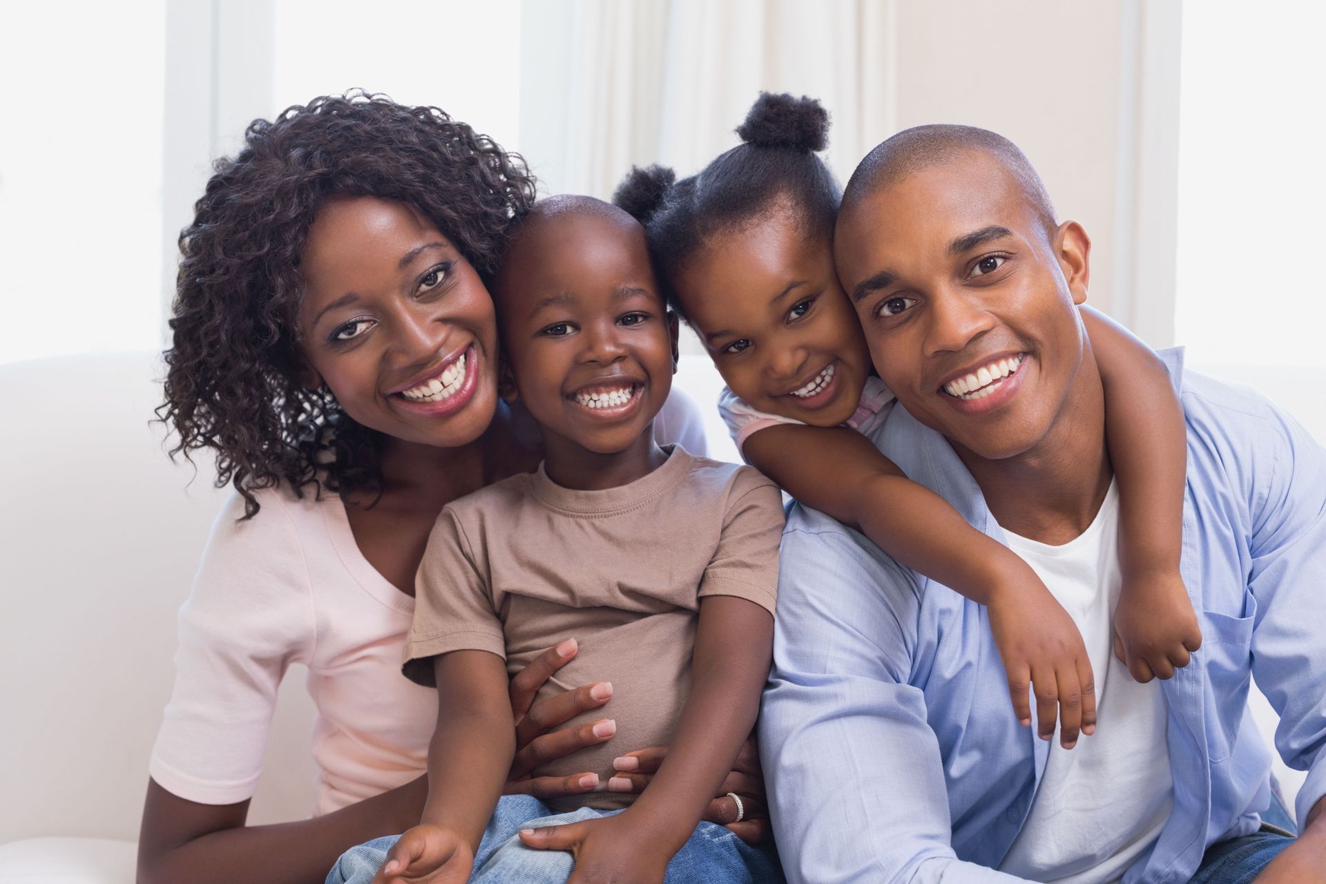 A family is posing for a picture while sitting on a couch.