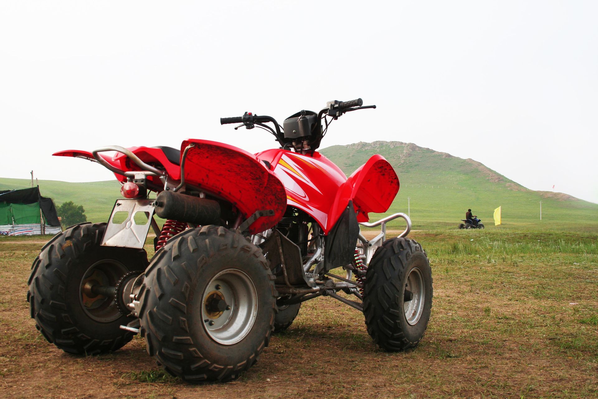 A red atv is parked in a grassy field.