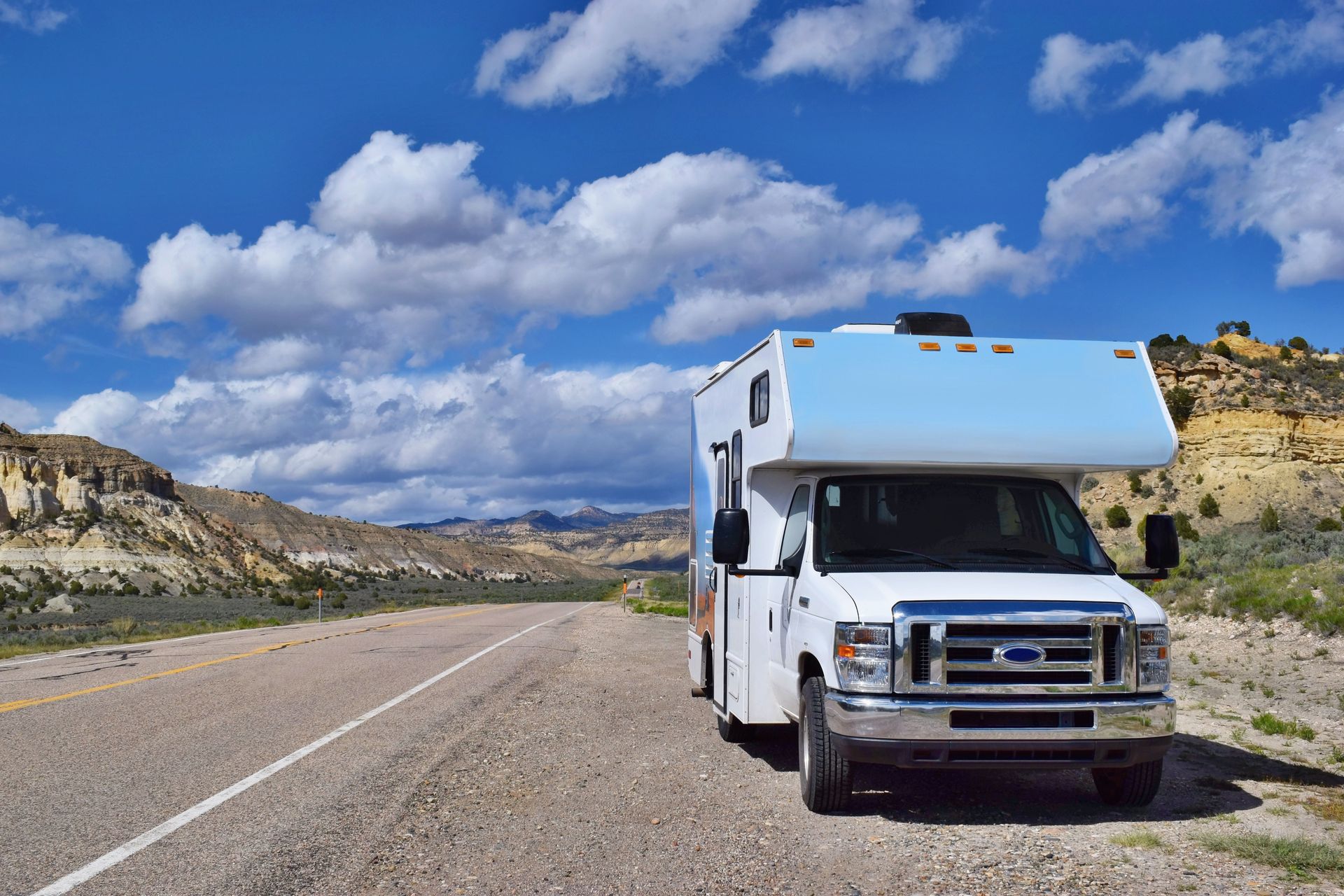 A white rv is parked on the side of the road.