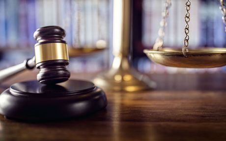 A judge 's gavel and scales of justice are on a wooden table.