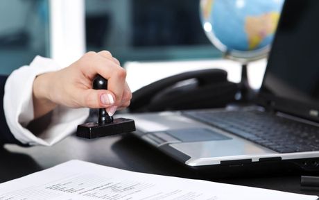 A person is stamping a document in front of a laptop