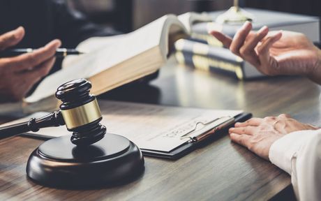 Two people are sitting at a table with a judge 's gavel and a book.