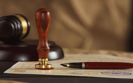 A pen is sitting on a piece of paper next to a wooden judge 's gavel.