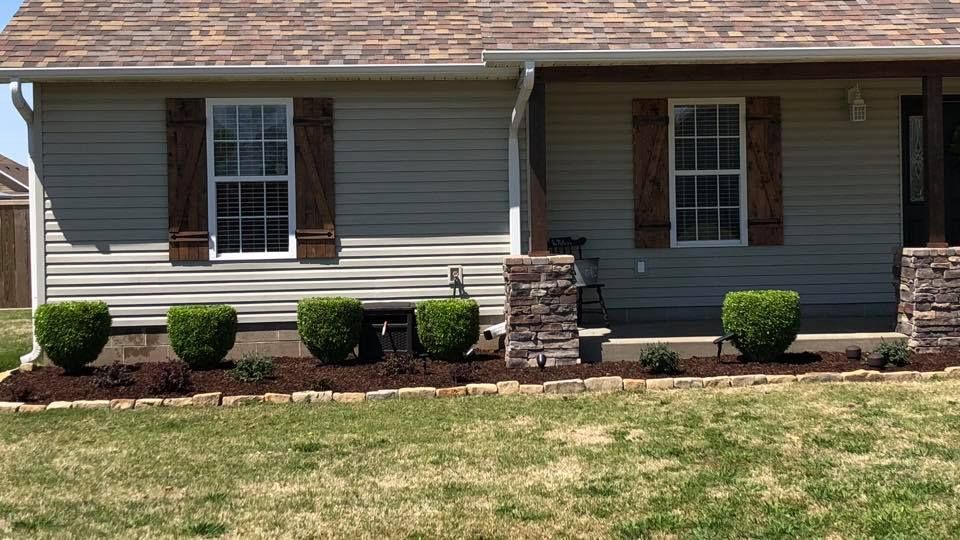 A house with a stone pillar in front of it and a lush green yard