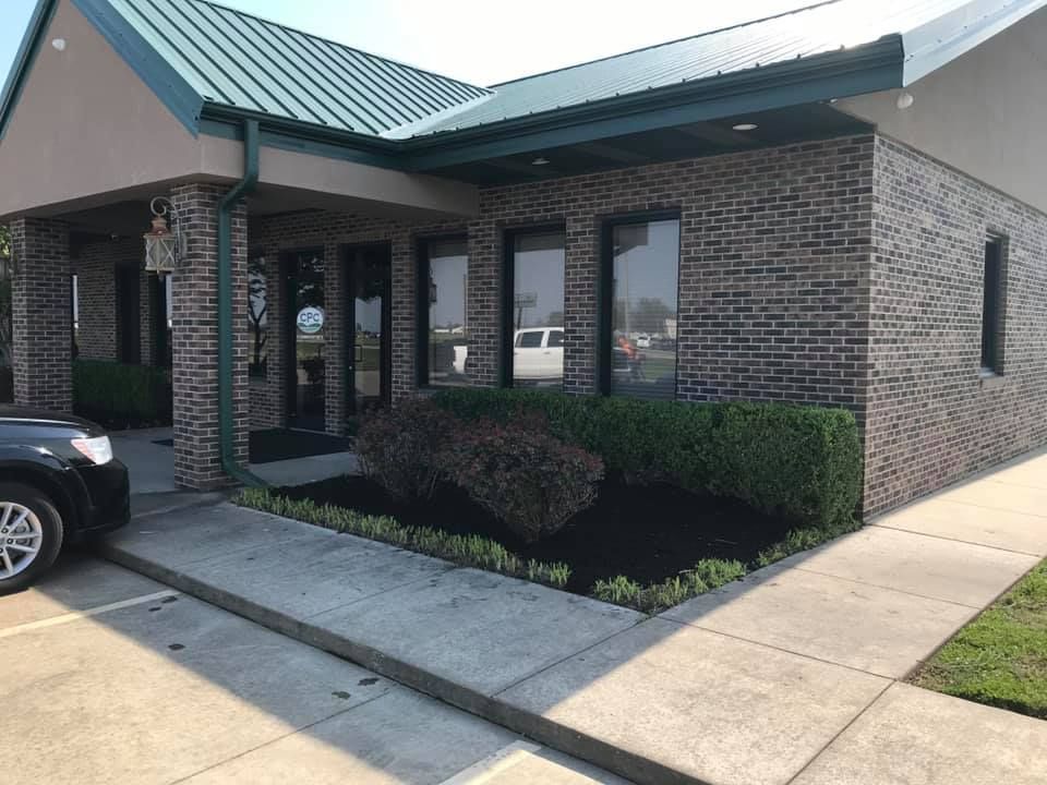 A brick building with a green roof and a car parked in front of it
