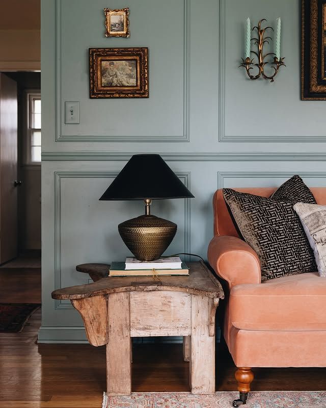 Elegant living room corner with a peach sofa, black lamp on a rustic wooden side table, and framed wall art.
