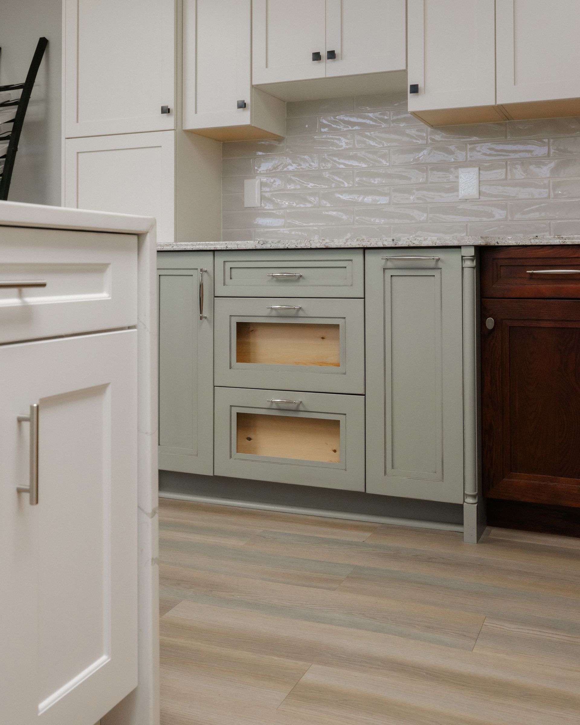 Kitchen with sage green lower cabinets, white upper cabinets, and a light wood floor