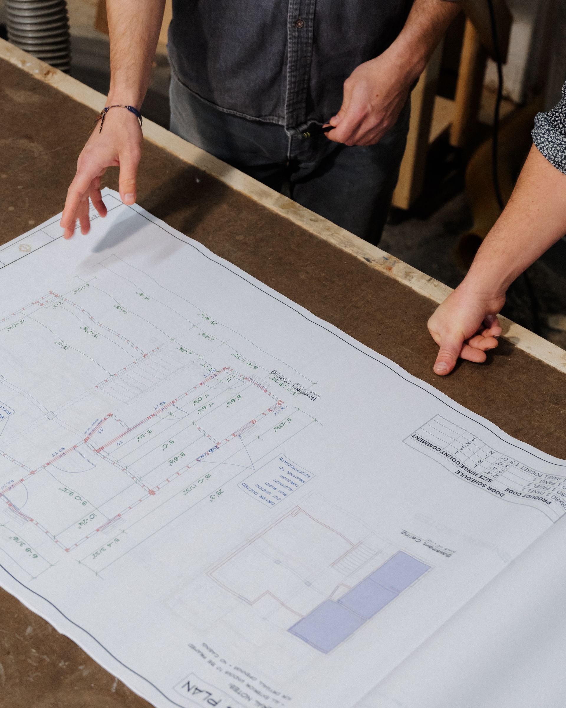 Two people leaning over a large architectural blueprint on a table