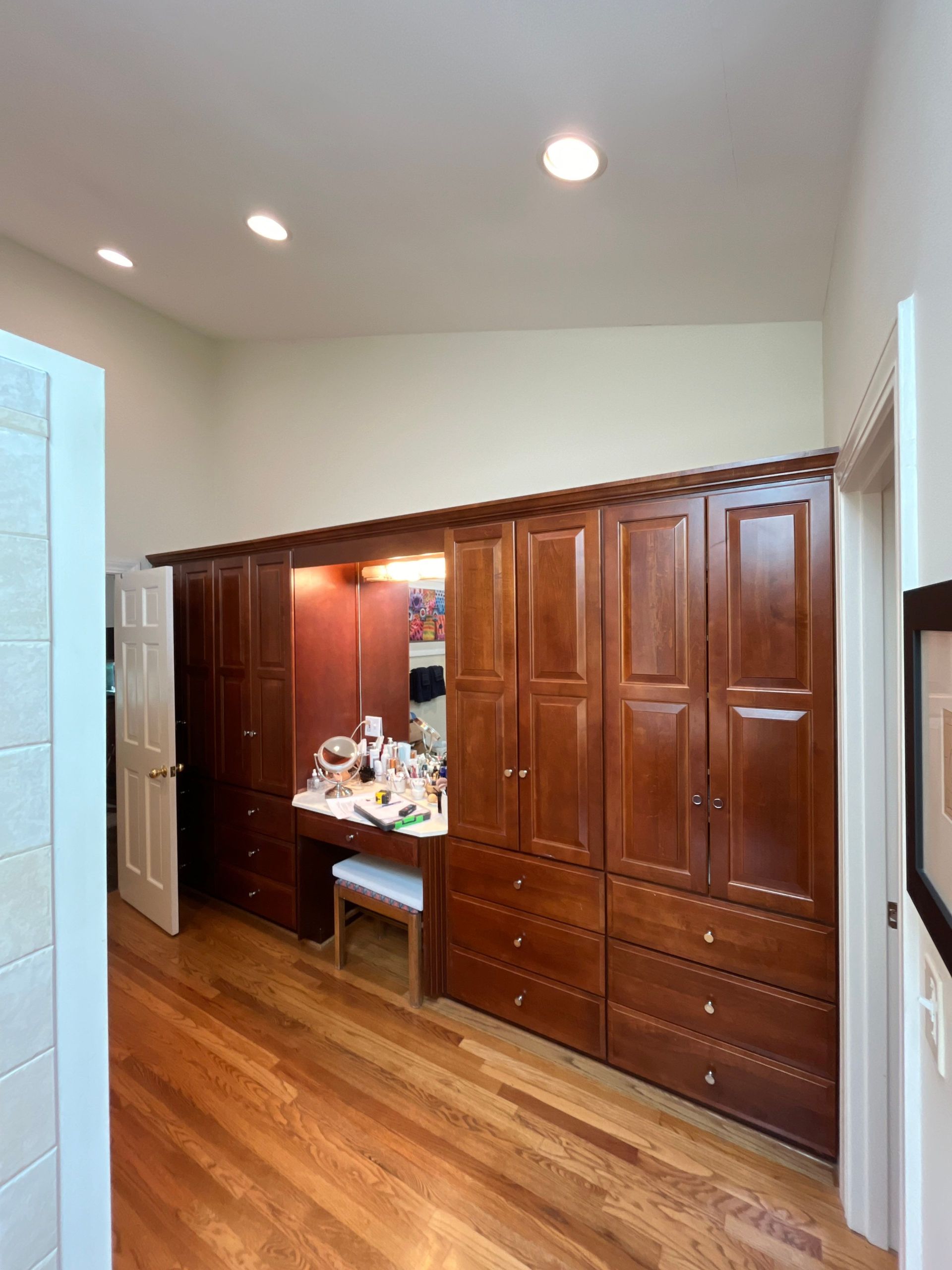 Wooden hallway cabinets with a mirror, floral arrangement, and warm recessed lighting in a home interior