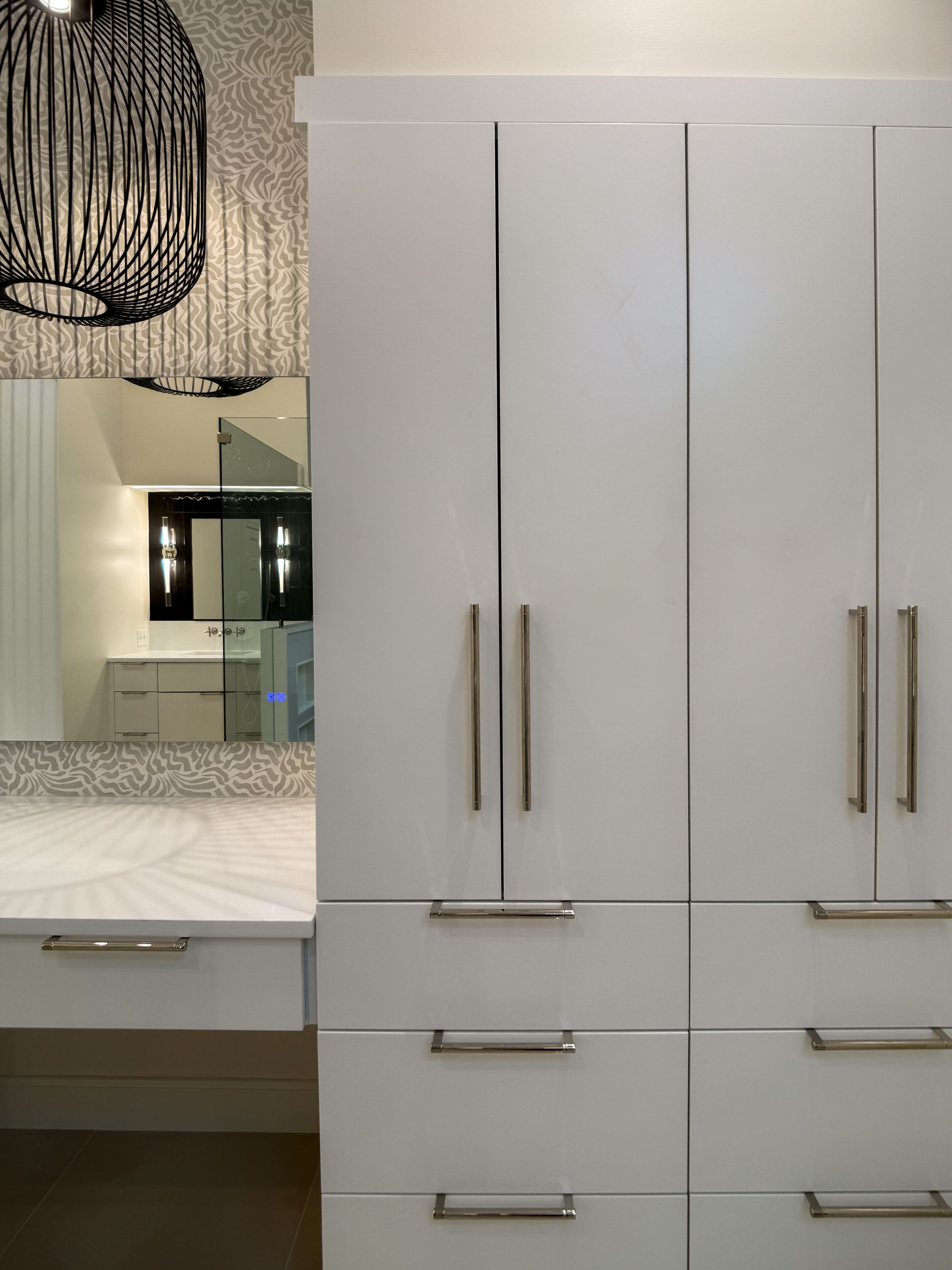 Modern white bathroom vanity with tall cabinets, drawers, and a lit mirror