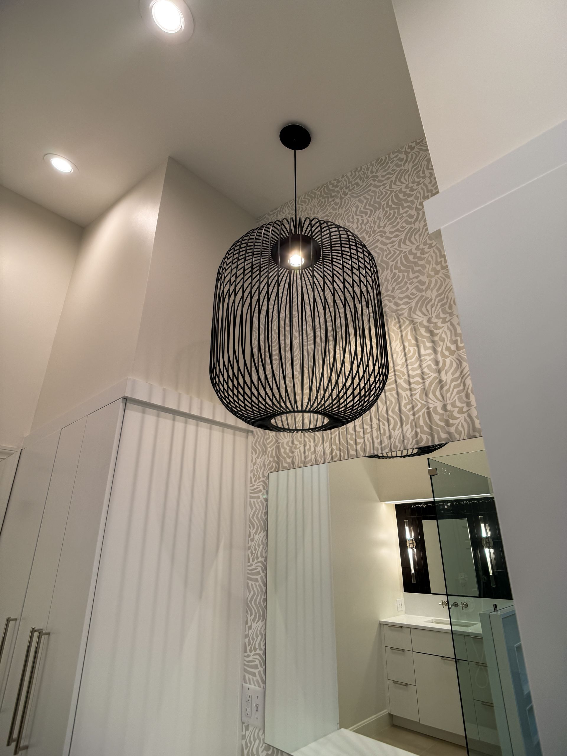 Modern hallway with a black pendant light, patterned wallpaper, and mirrored wall panel.