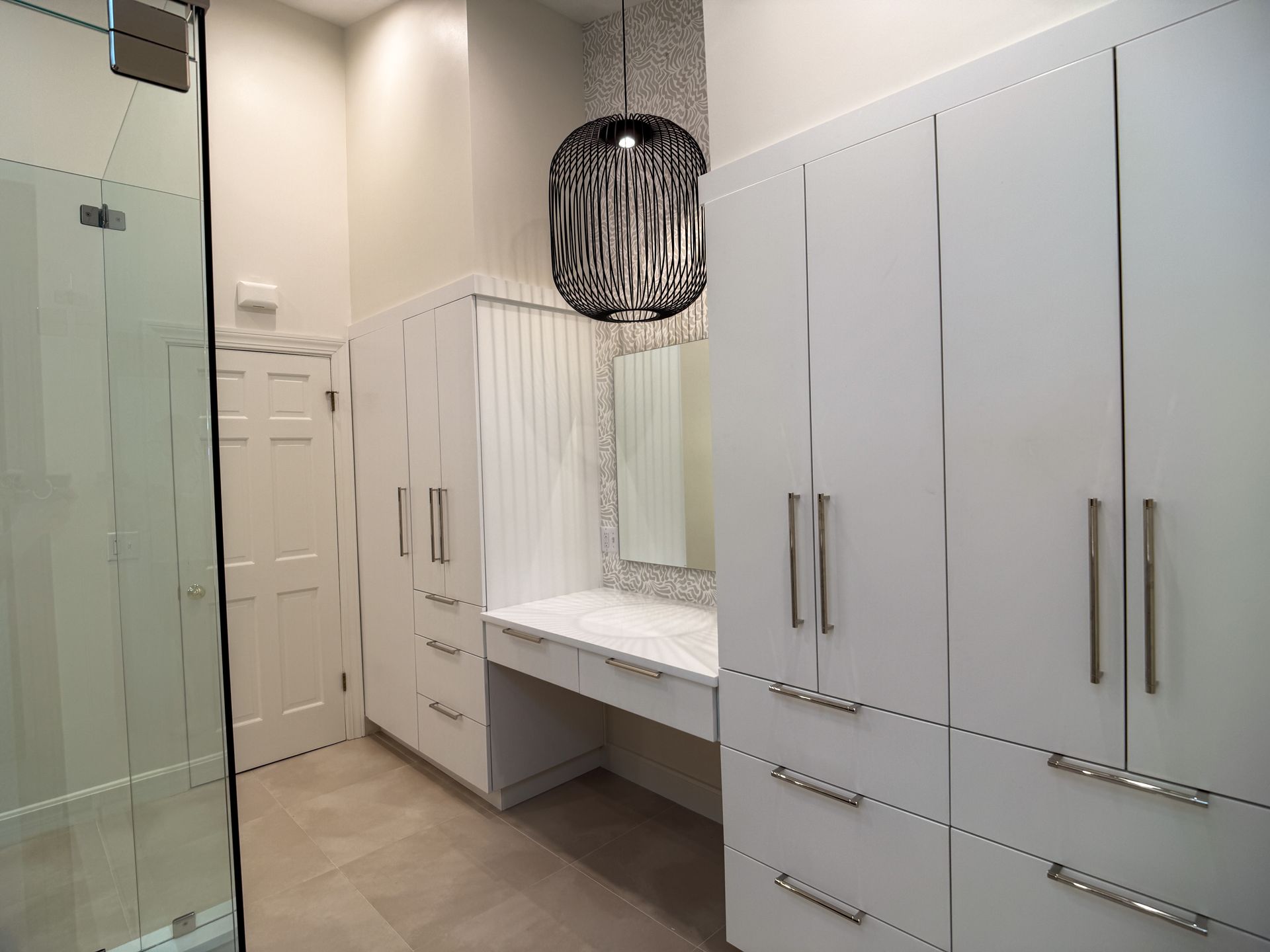 Modern white bathroom vanity with large mirror, drawers, and a glass shower enclosure