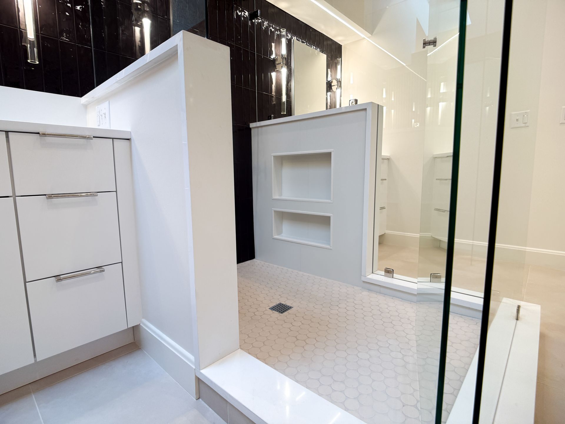 Modern bathroom with white vanity, tiled shower, and built-in wall shelves