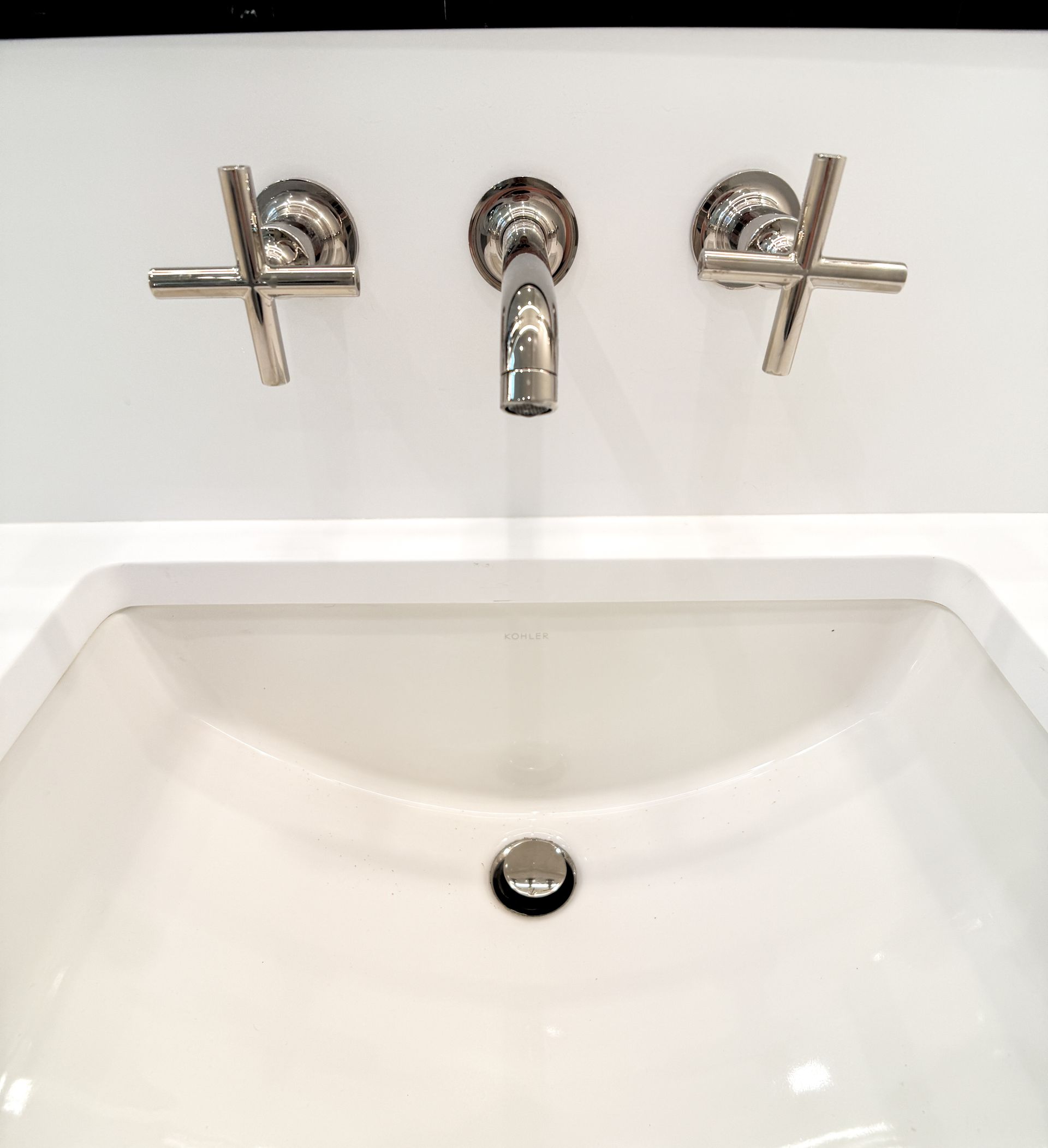 Chrome bathroom sink faucet with two cross handles above a white basin