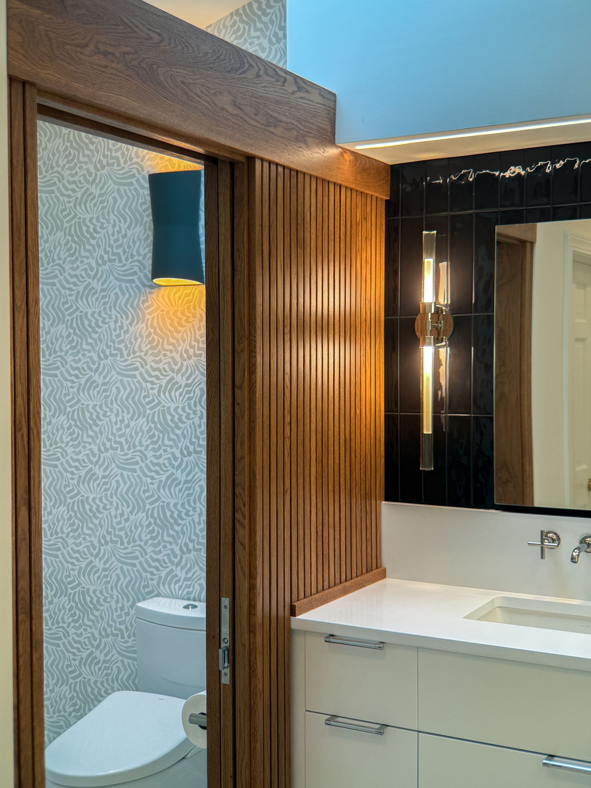 Modern bathroom vanity with mirror, sink, wood slat wall, and frosted glass shower door