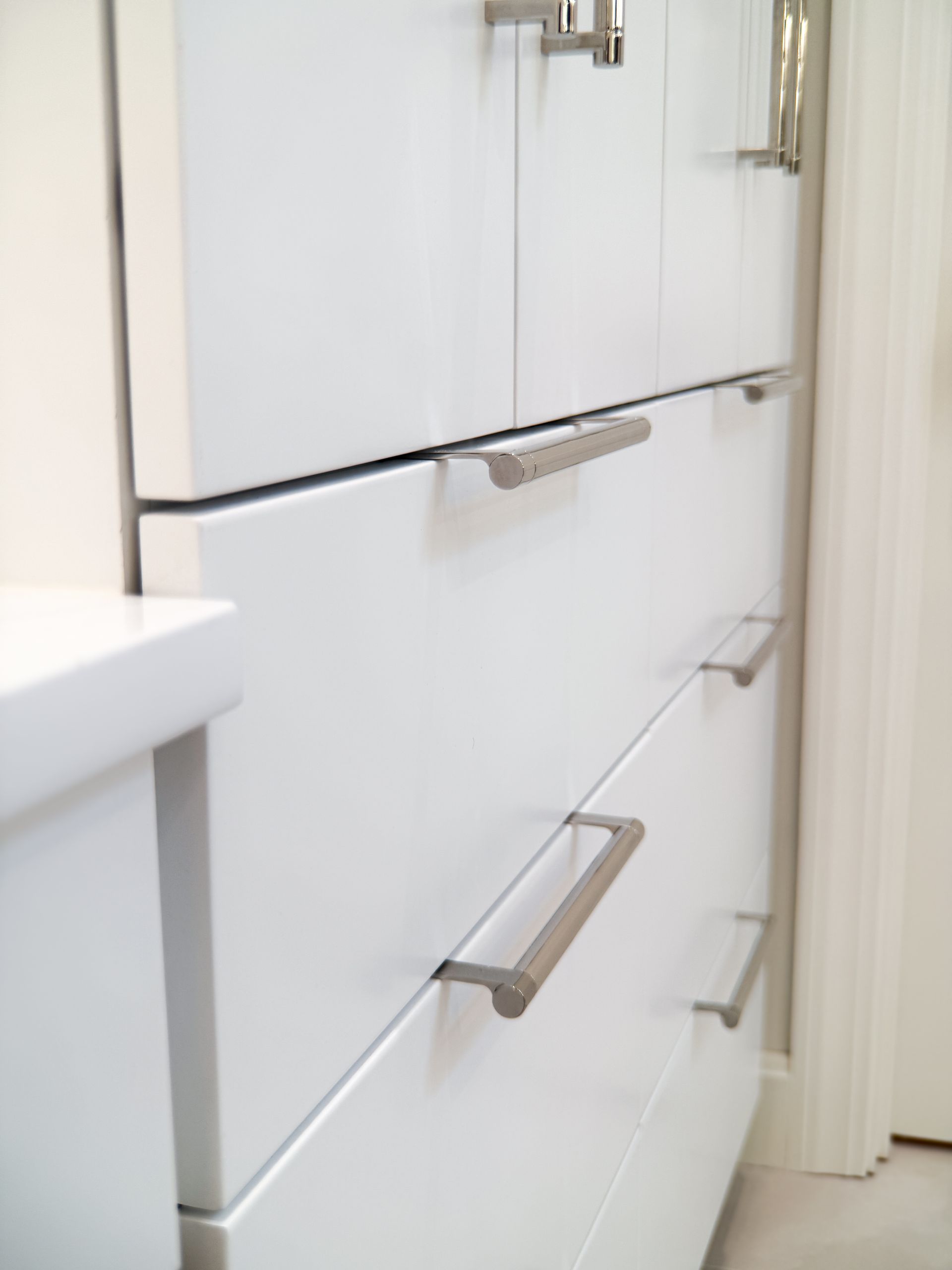 White dresser with silver handles in a bright hallway or room