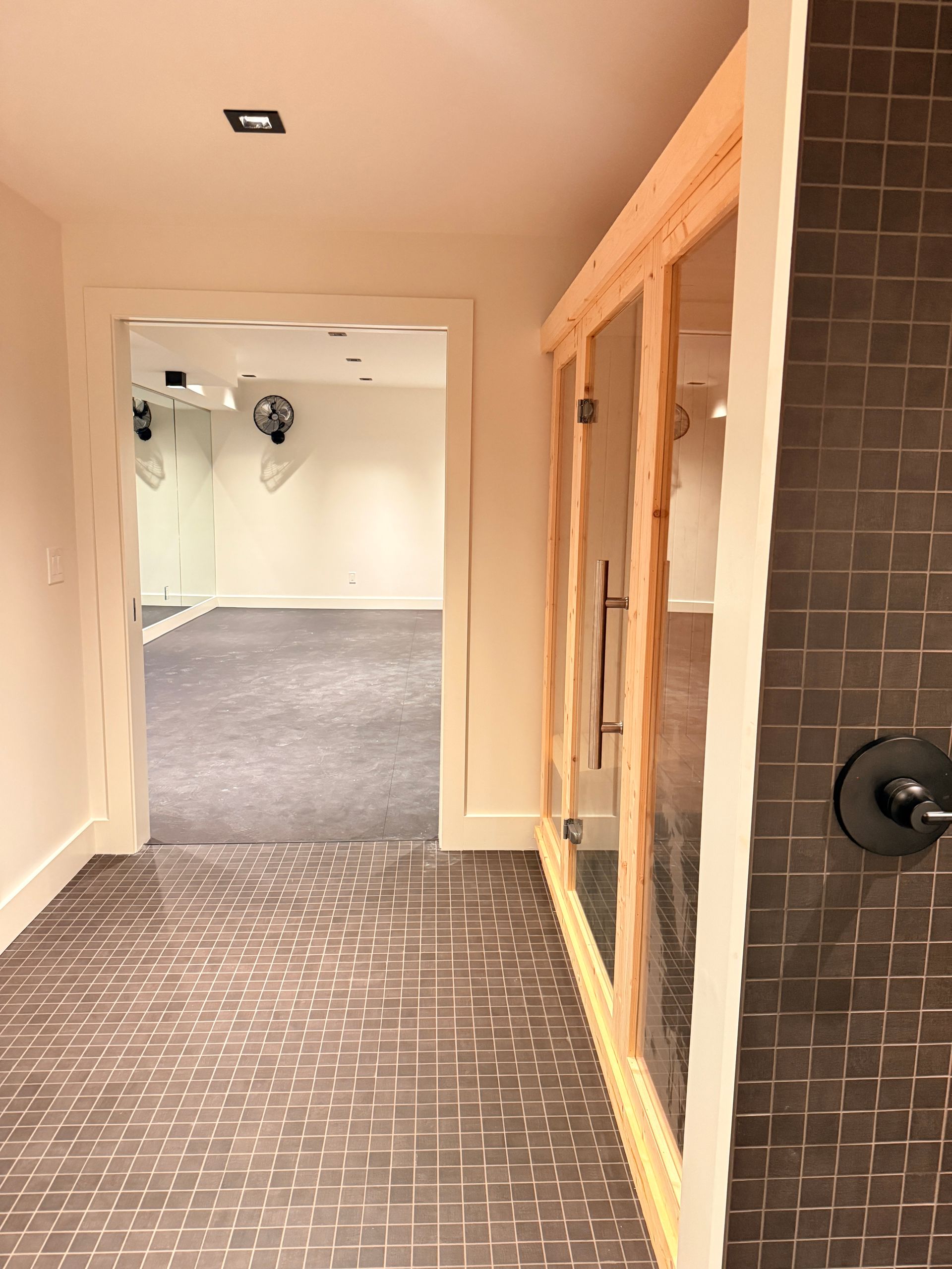 Hallway with patterned carpet, white walls, wood-framed glass doors, and a tiled column on the right
