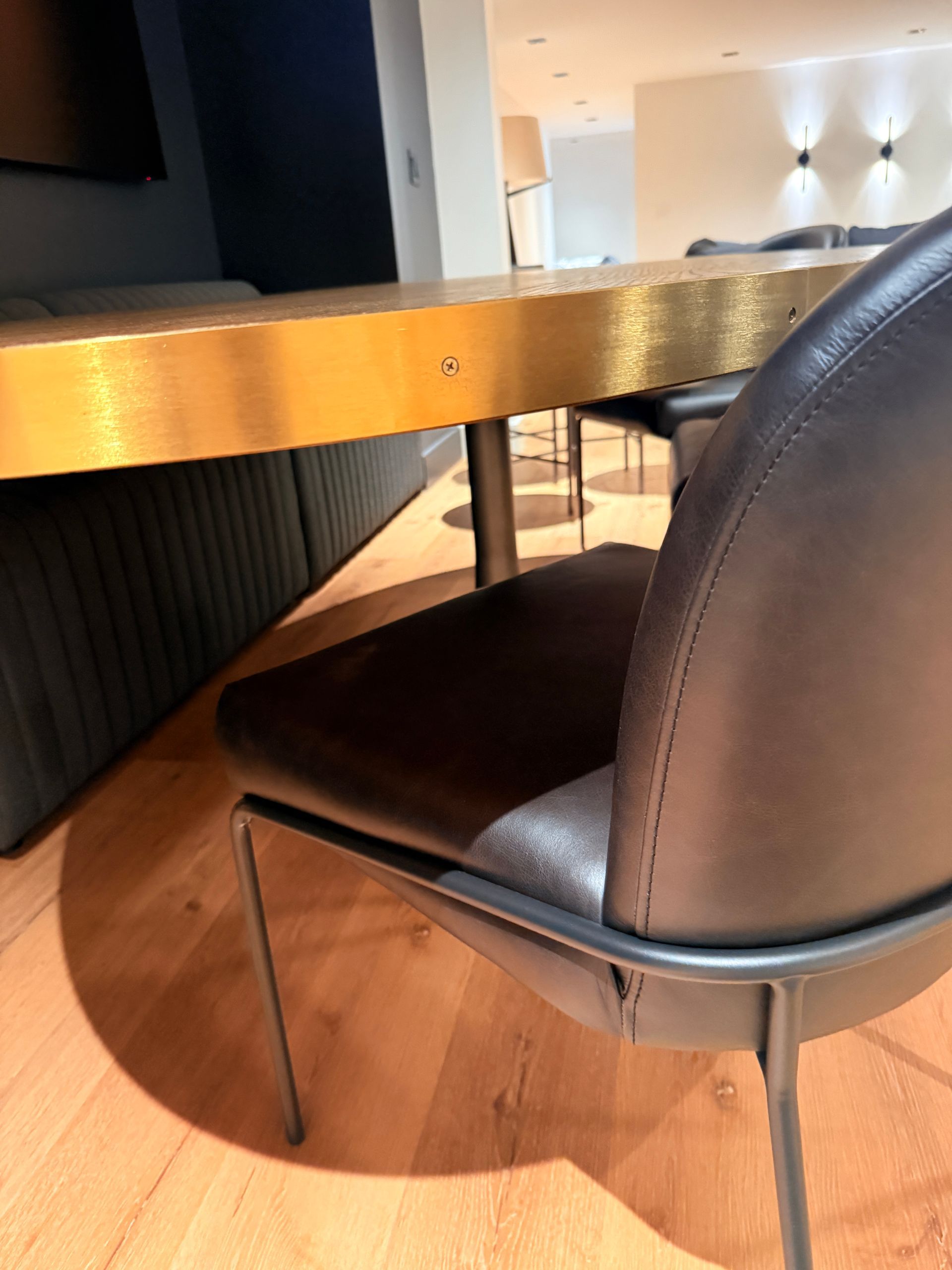 Black chair beside a wooden table in a modern dining area with warm lighting