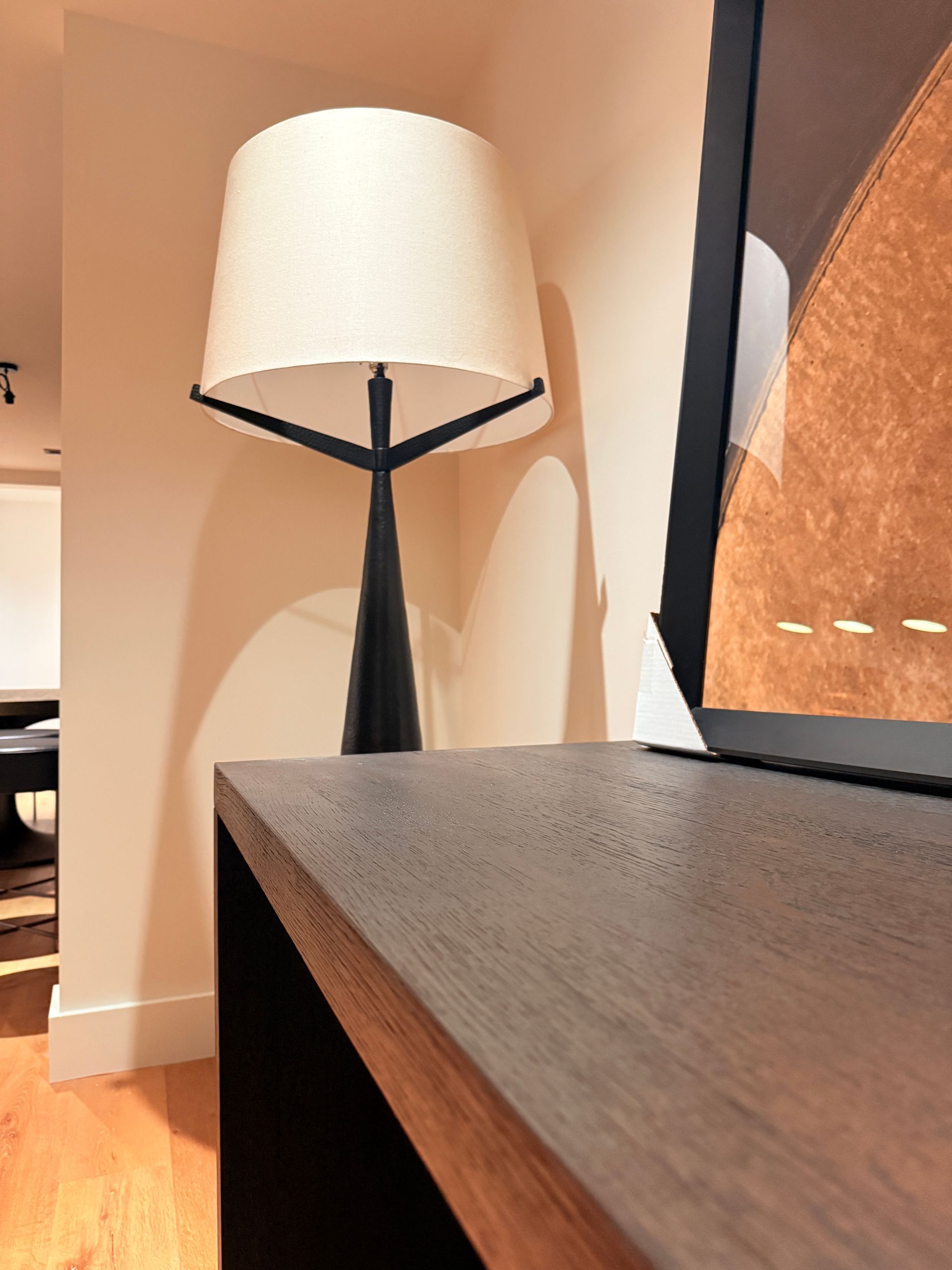 Black table lamp beside a wooden desk in a softly lit interior room