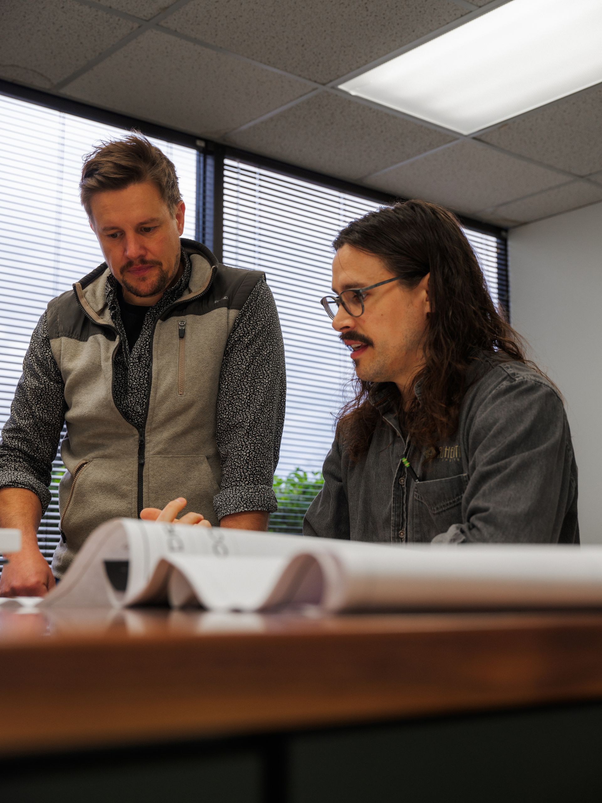 Two people reviewing documents at a table in an office meeting room