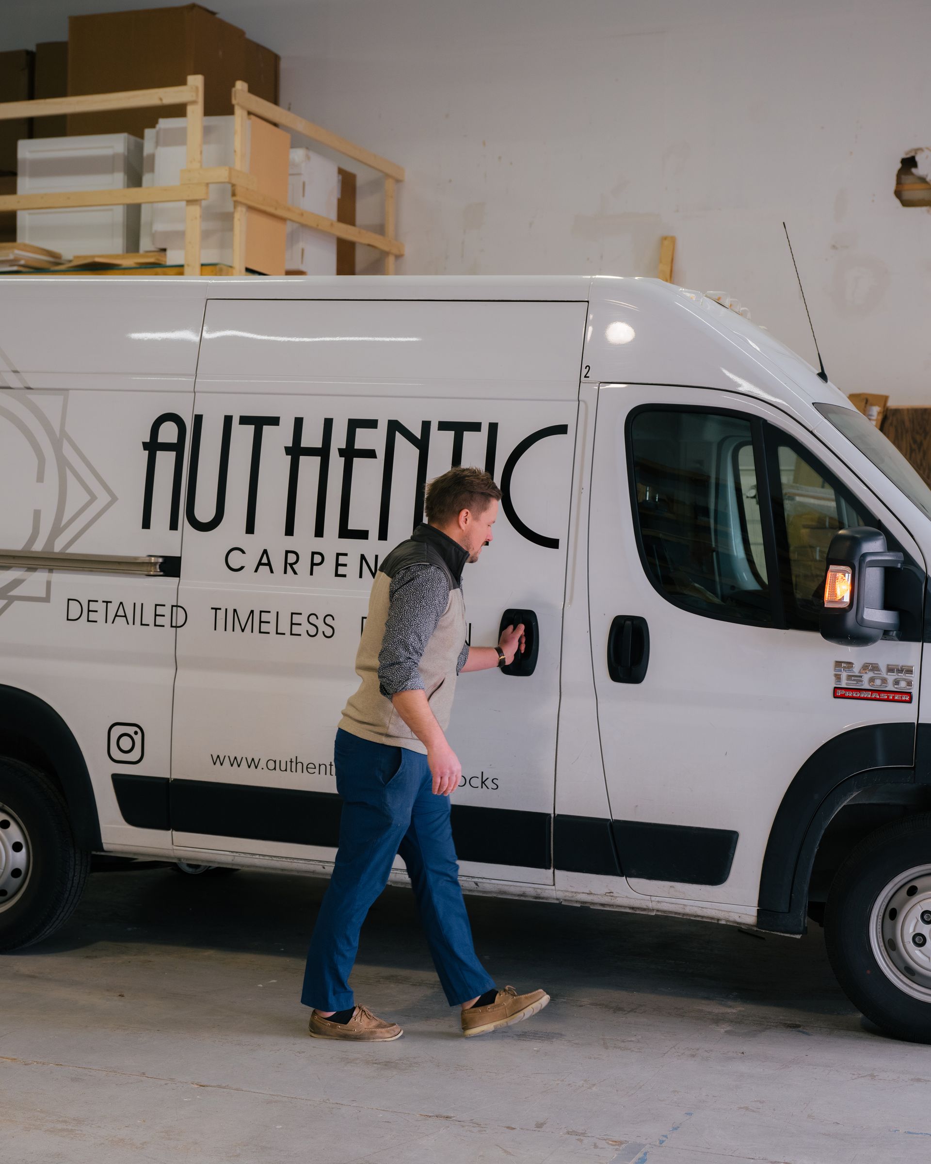 Person walking beside a white service van with “AUTHENTIC” branding in a garage or warehouse.