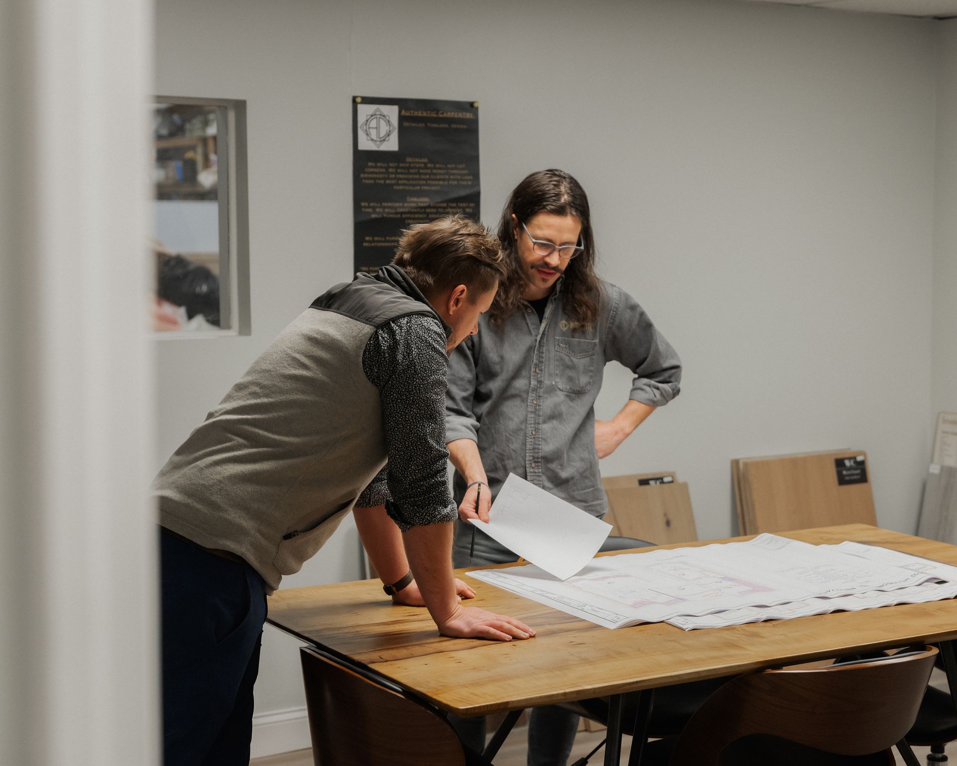 Two people reviewing papers on a table in a meeting room.