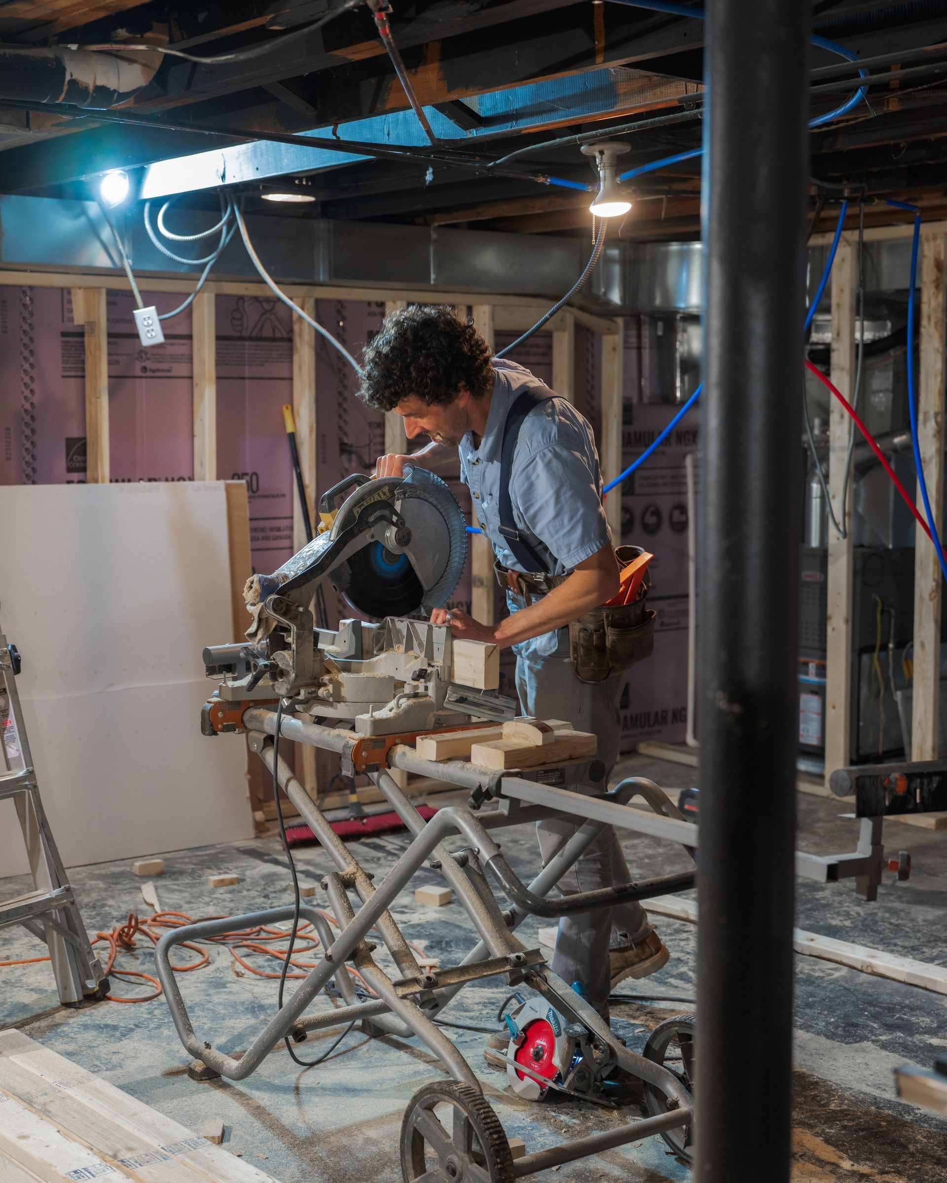 Person using a power tool at a workbench in a dusty basement workshop