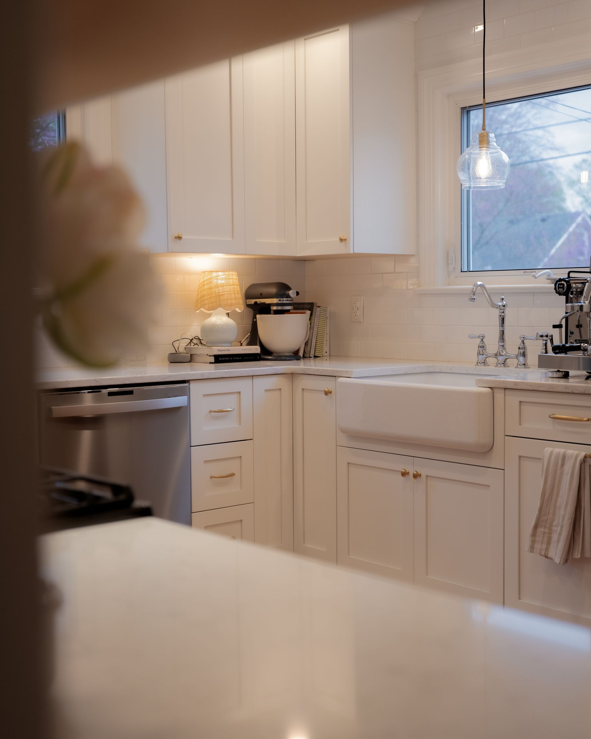 Bright white kitchen with cabinets, farmhouse sink, countertop appliances, and a window over the sink.