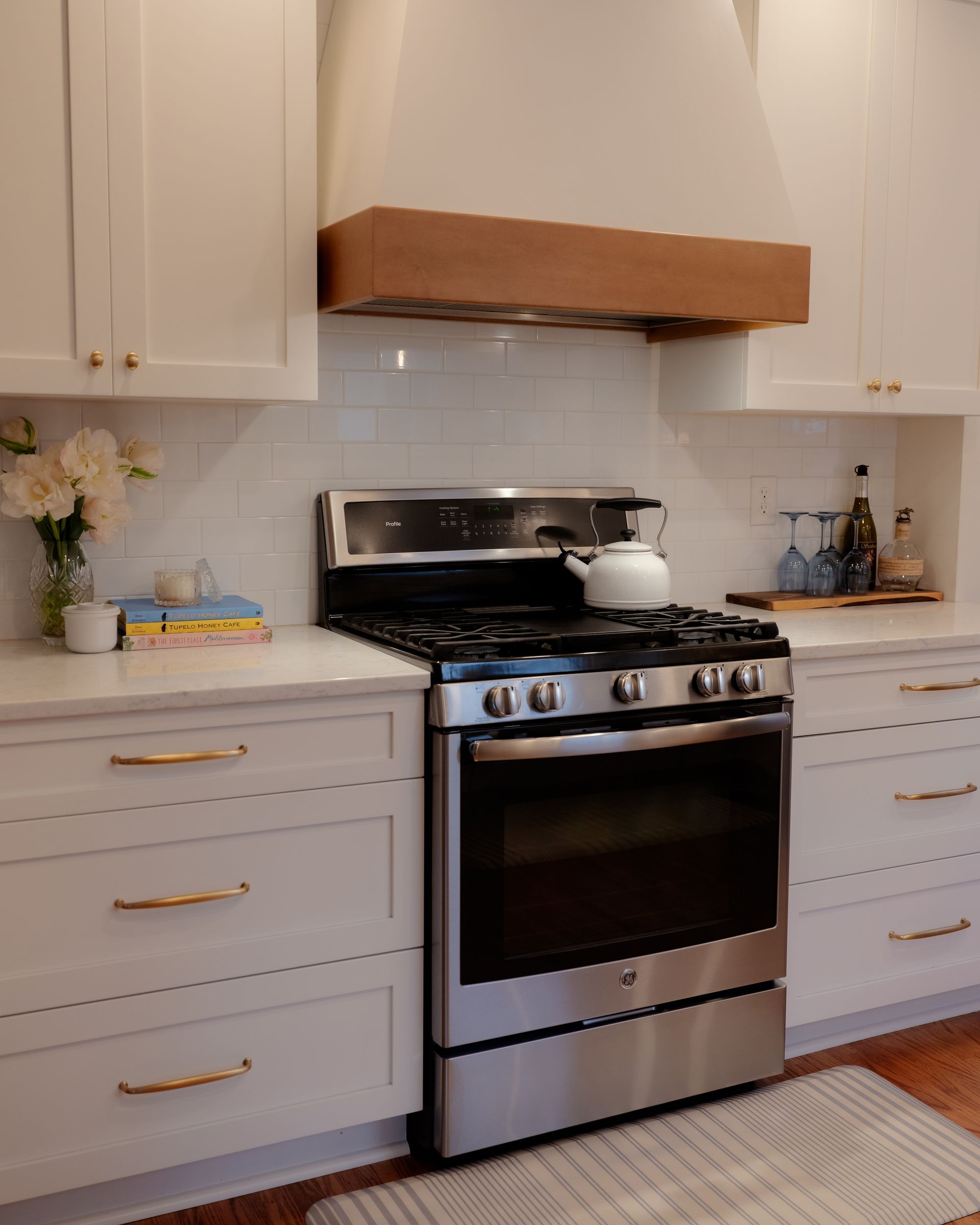 Modern kitchen with stainless steel stove, white cabinets, and a wooden range hood