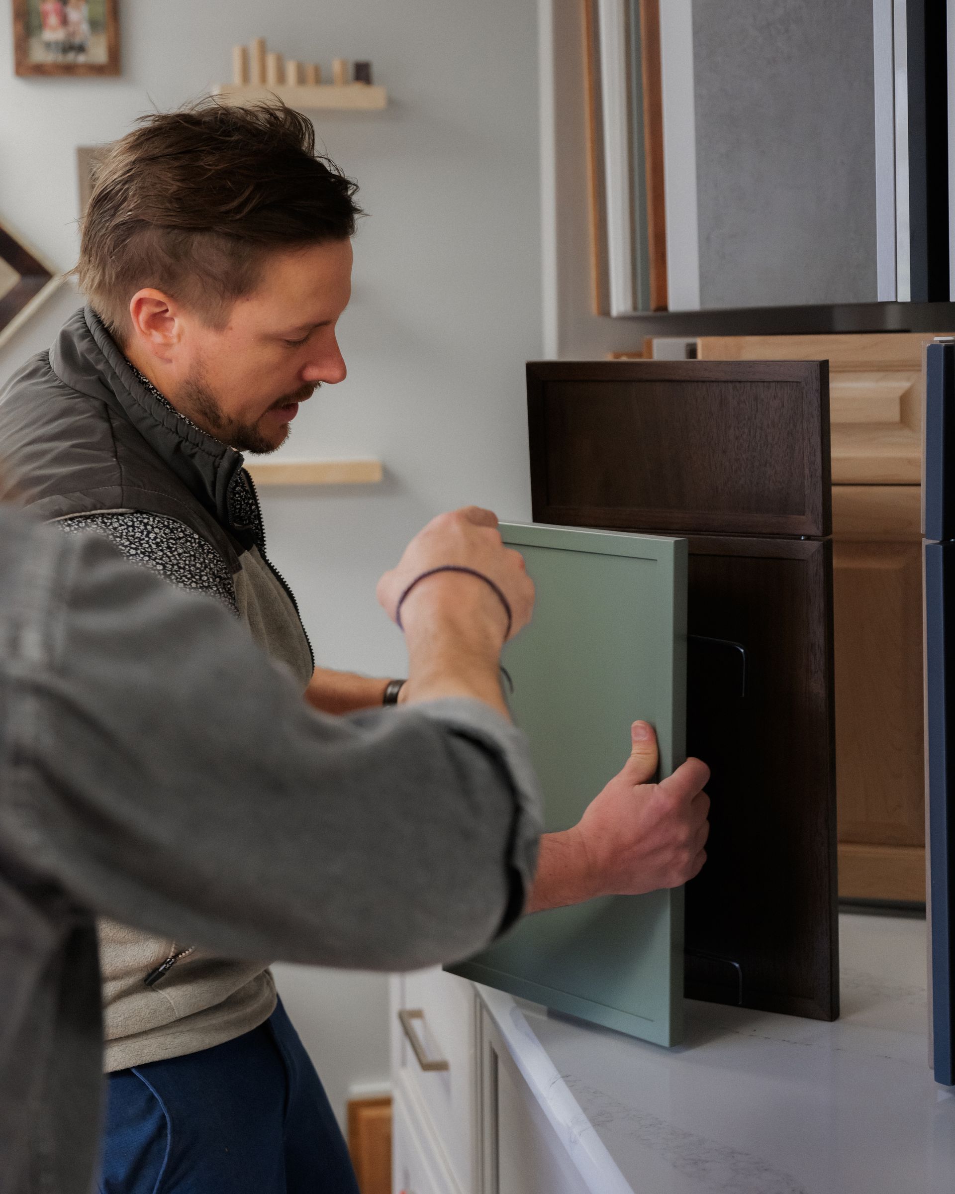 Person installing a green cabinet door in a modern kitchen or office cabinet.