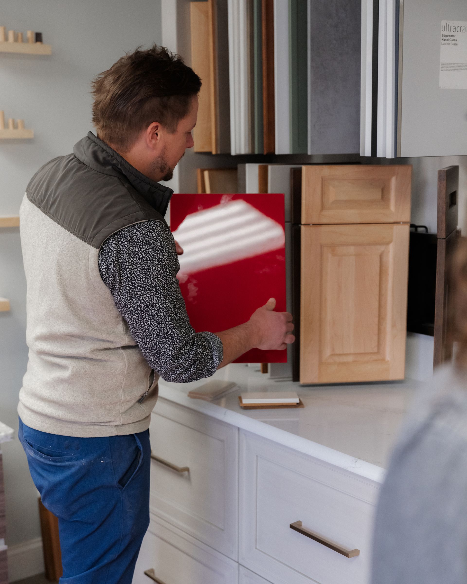Person unloading a red tray from a kitchen cabinet in a bright kitchen