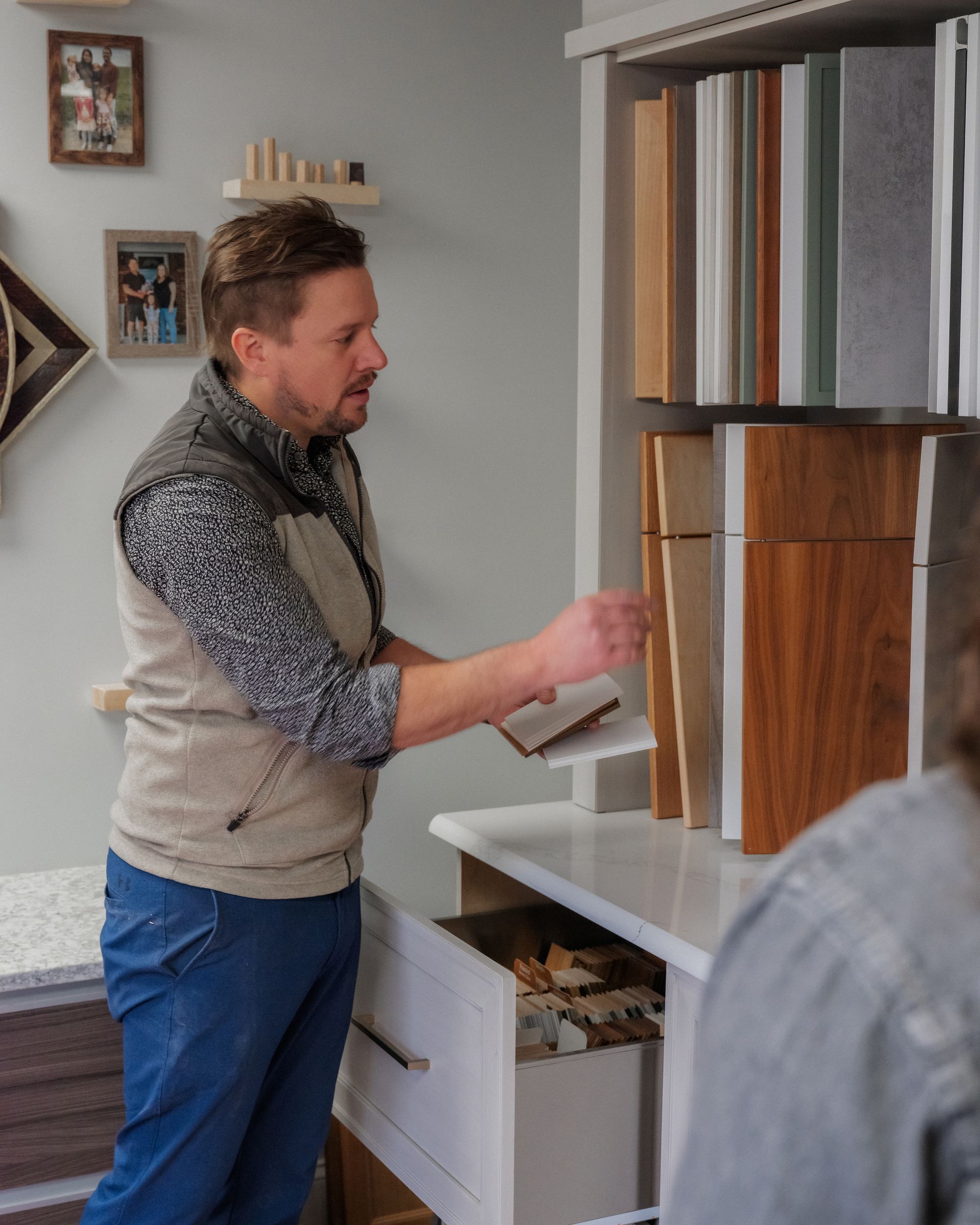 Man examining fabric samples on a display shelf in a showroom