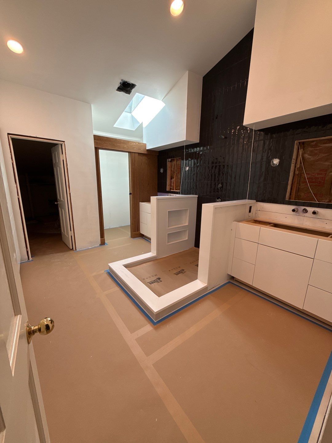 Small kitchen with white cabinets, dark backsplash, skylight, and a raised island countertop