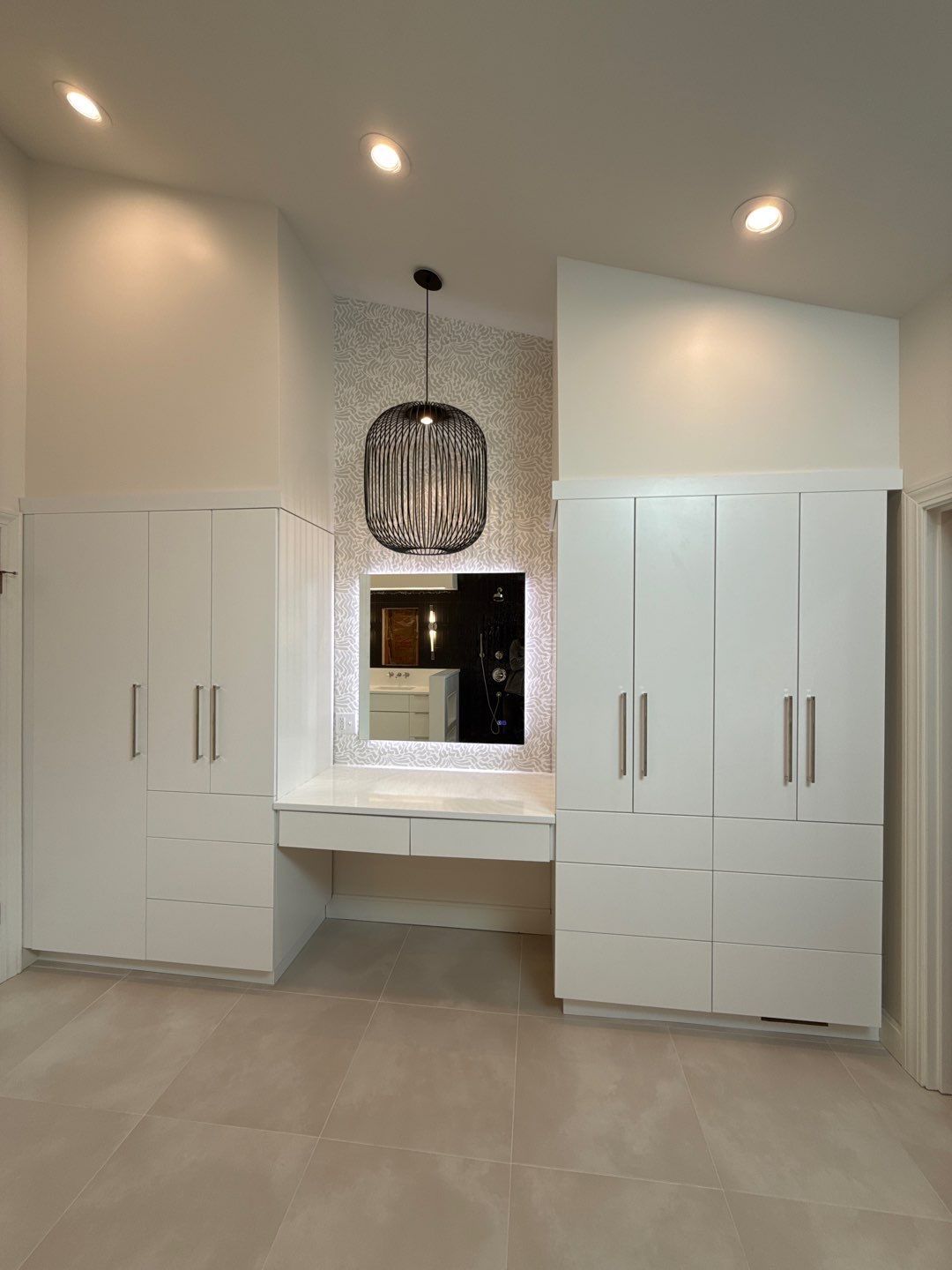 Modern bathroom vanity nook with double white cabinets, central mirror, and beige tile floor.