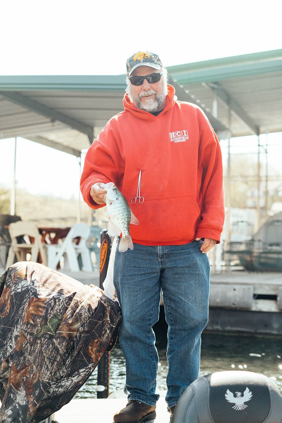 Man in red hoodie holding a fish on a boat.