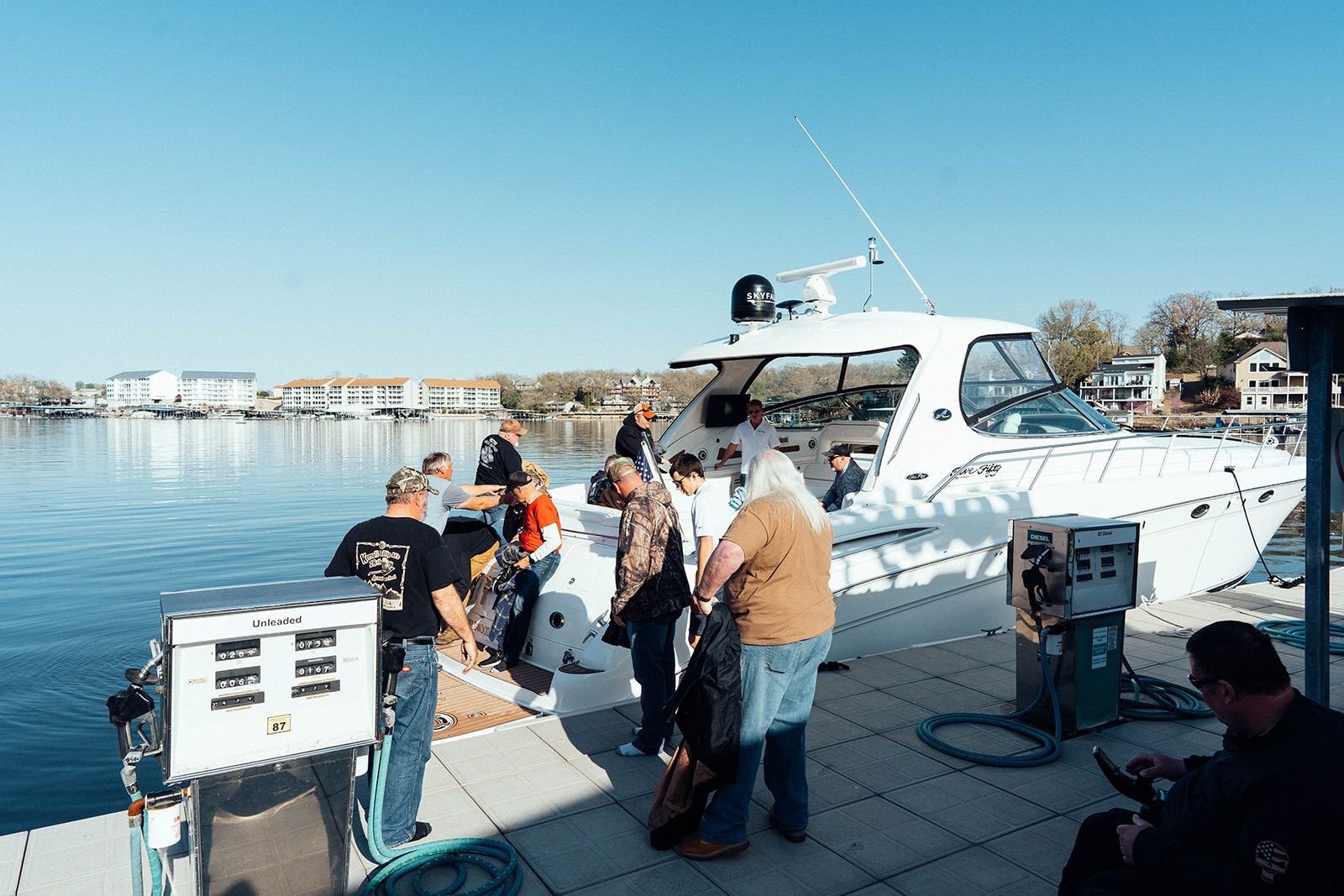 People fueling a white boat at a dock on a sunny day.