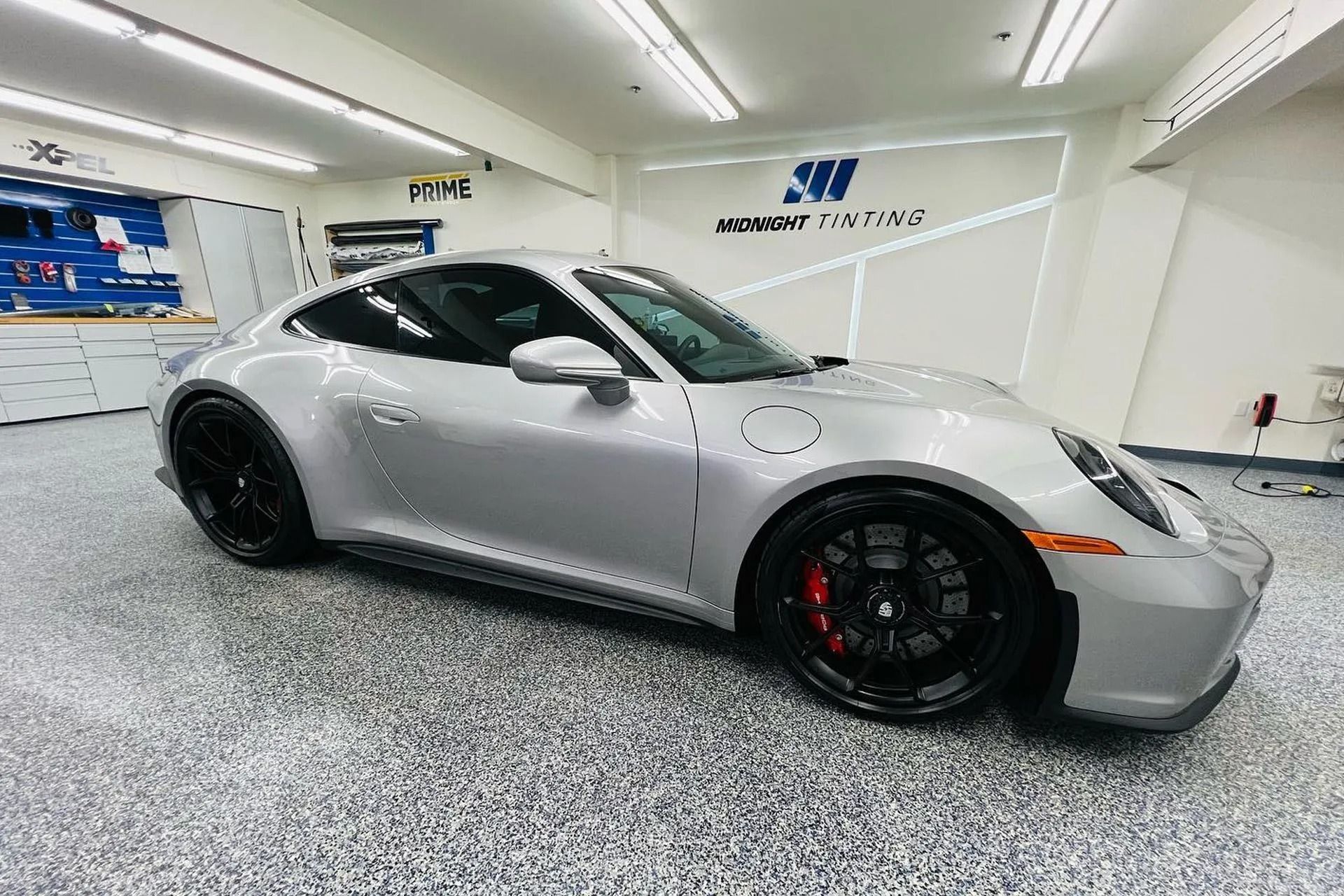 Silver Porsche sports car in a garage with black wheels and red brake calipers.
